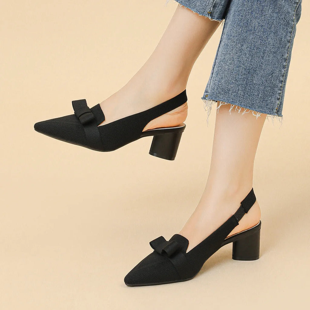 Women's black closed toe high heel sandals with a bow detail and an ankle strap on a rubber sole.
