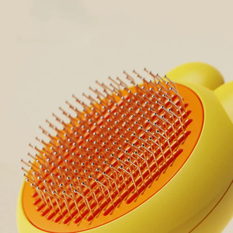 Self-cleaning cat brush with release button showing stainless steel teeth with rubber tips