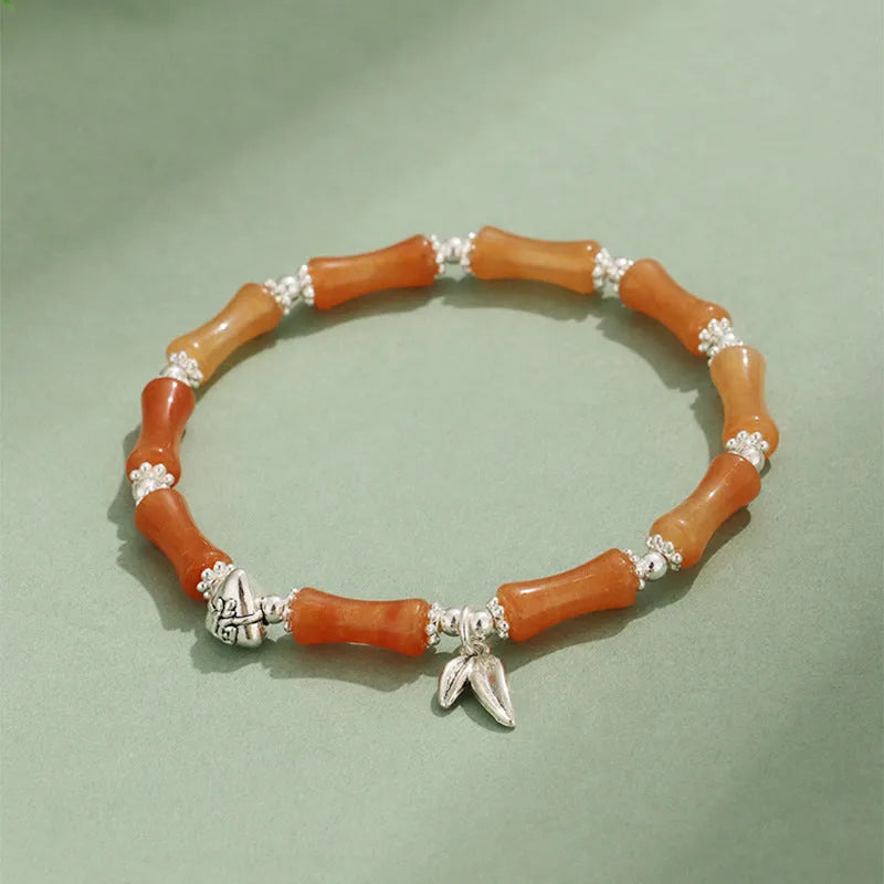 Women's green aventurine crystal bracelet with bamboo, strawberry quartz, and jade beads on wrist.