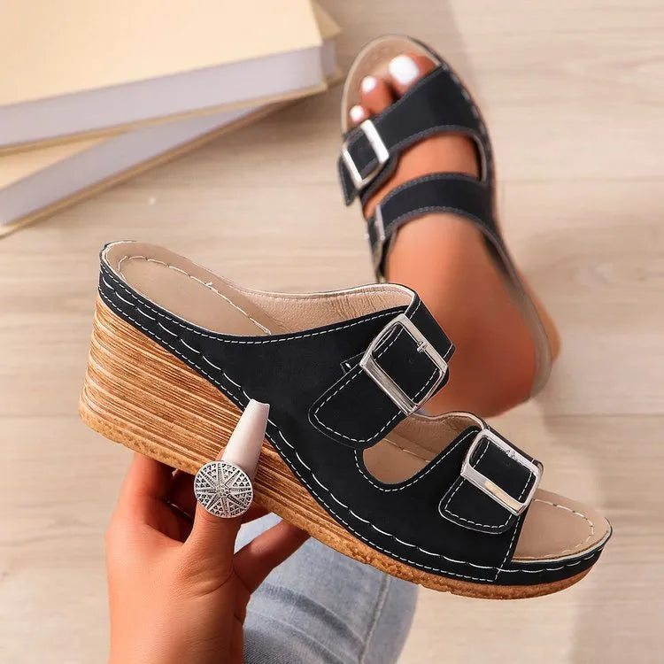 Creamy-white women's wedge slippers with a buckle strap on a black sole.