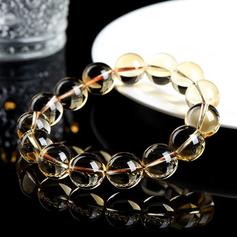 Natural yellow citrine scattered beads bracelet on a wrist, showing polished gemstones on a knotted cord.