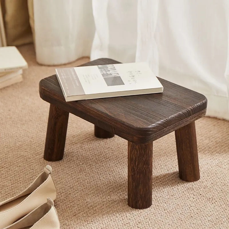 Distressed solid wood stool for changing shoes with a bracket frame structure.