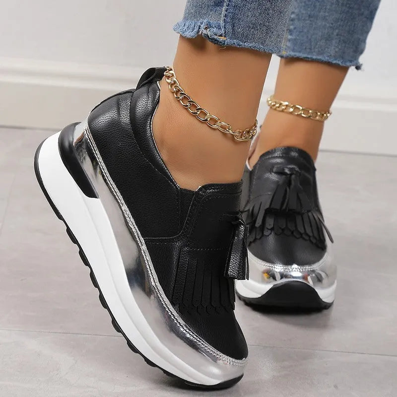Women's black casual platform shoes with tassel decoration and a distinctive English muffin wedge heel.
