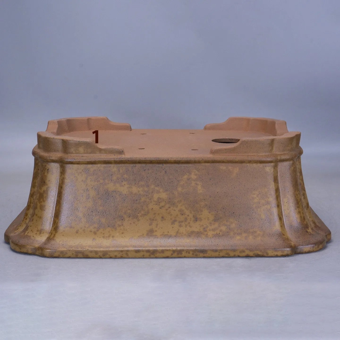 Large rectangular purple sand flowerpot with angled drainage base on a wooden patio.