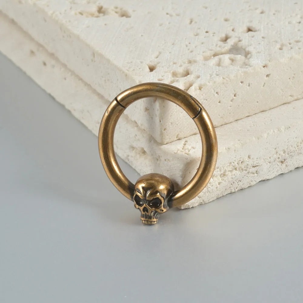 A pair of vintage-style copper earrings with an embossed ghost head design on a stud post, showing an antique silver finish.