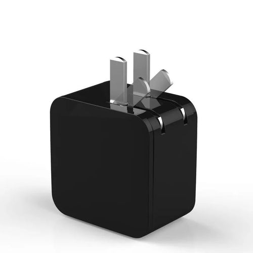 Black dual USB fast charger with digital display showing voltage and current, next to UK plug