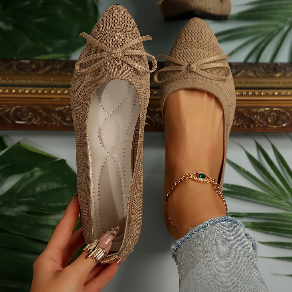 Women's knitted flat shoes with a bow detail and pointed toe in various colours on a plain background.