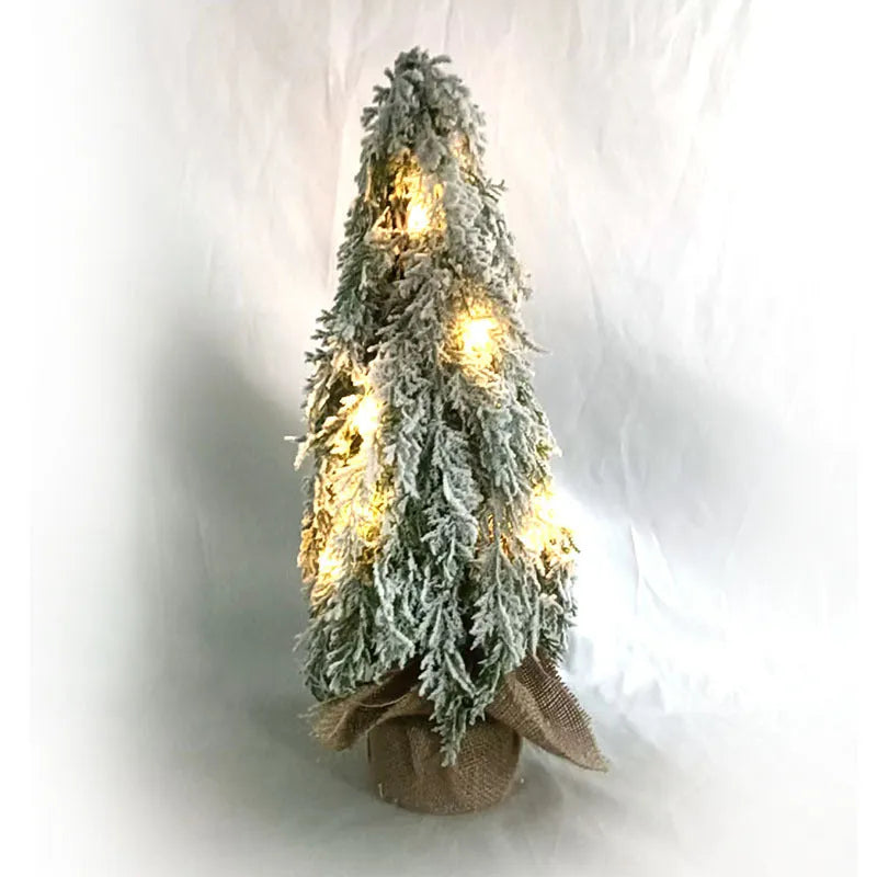 Small 24-inch white artificial Christmas tree with LED lights and snow effect on a desktop