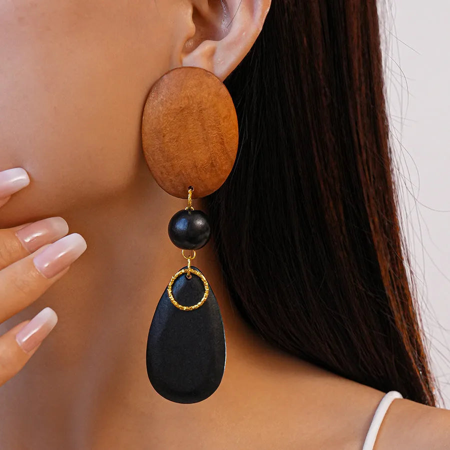 Pair of brown and black wooden retro earrings with an elliptical shape and silver needle detail.