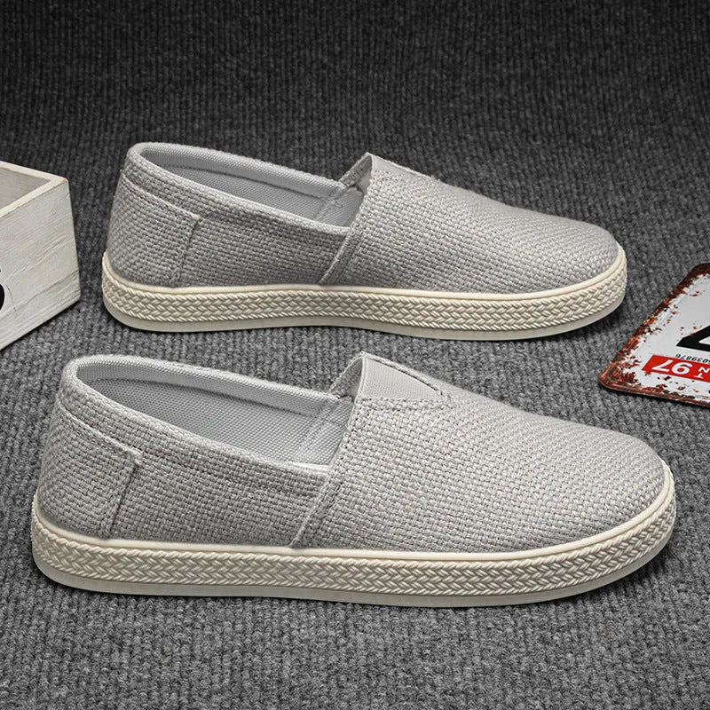 Men's beige canvas slip-on shoes with round toe and PVC sole on neutral background