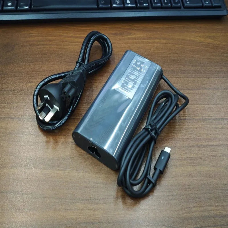 Black 65W USB-C laptop power adapter with multiple international plug attachments on white background