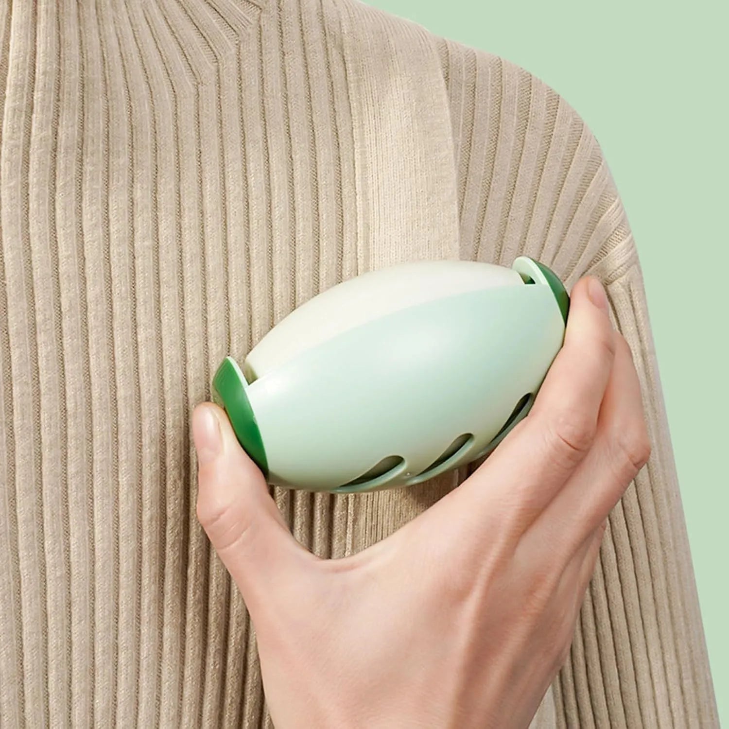 Green and white washable gel lint roller ball for pet hair removal on fabric.