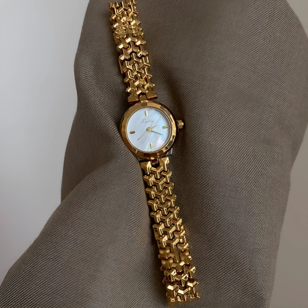 Women's thin 8mm alloy watch with white shell dial and gold strap on wrist