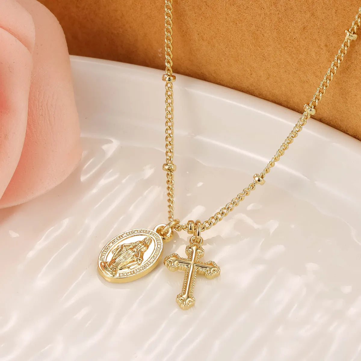 Geometric gold cross Virgin Mary pendant necklace on a chain with a lobster clasp.