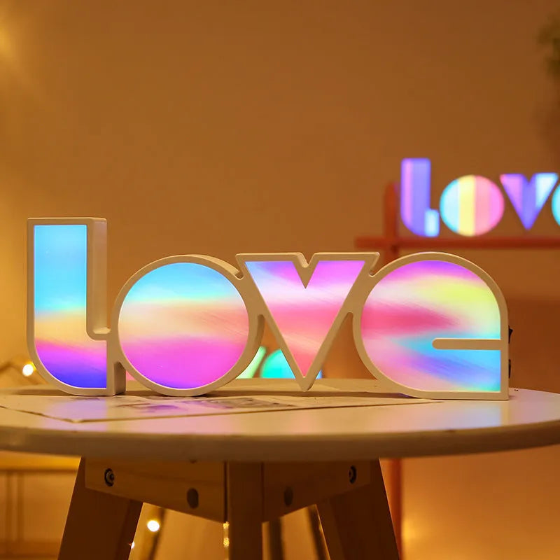 Rainbow coloured LED LOVE word light for Valentine's Day and wedding decoration on a table.