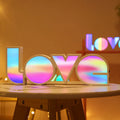 Rainbow coloured LED LOVE word light for Valentine's Day and wedding decoration on a table.