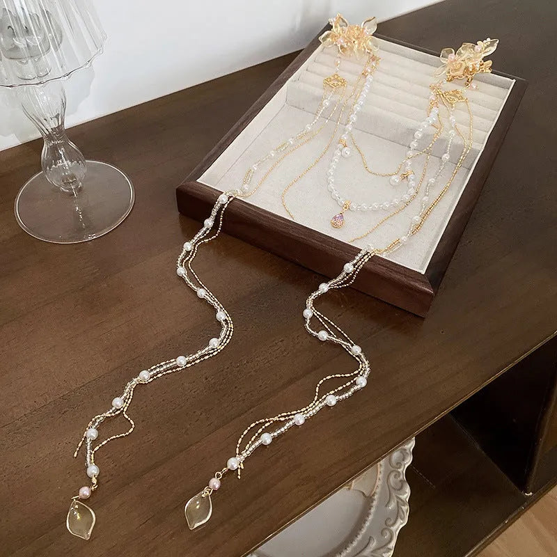 Gold-coloured women's hairpin with acrylic flower design featuring pearl, diamond, and long tassel decorative elements
