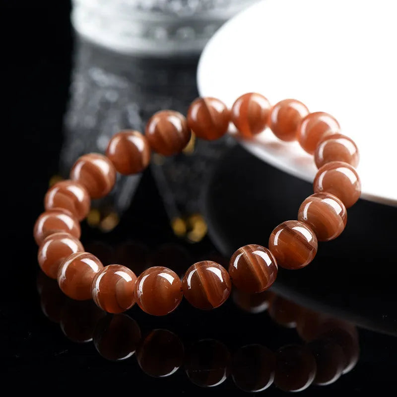 Natural Old Mine Rhodochrosite mineral bracelet with round beads in 6mm or 8mm size on a wrist.