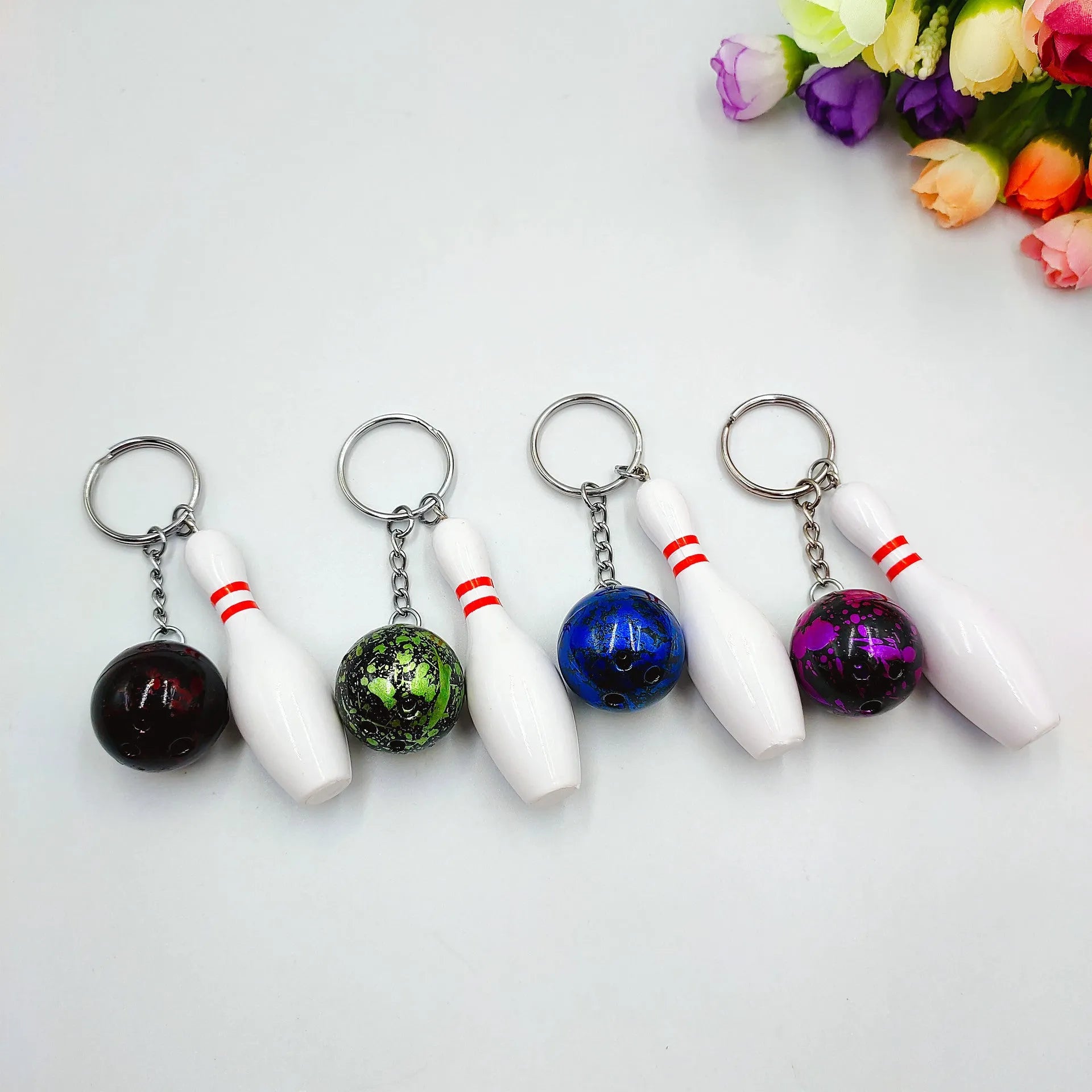 Mini bowling pin simulation keychain in blue, red, green, and purple colours on a metal ring.