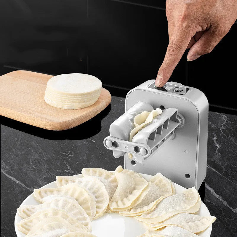 White automatic electric dumpling maker machine with USB cable, brush, and spoon on a kitchen counter.