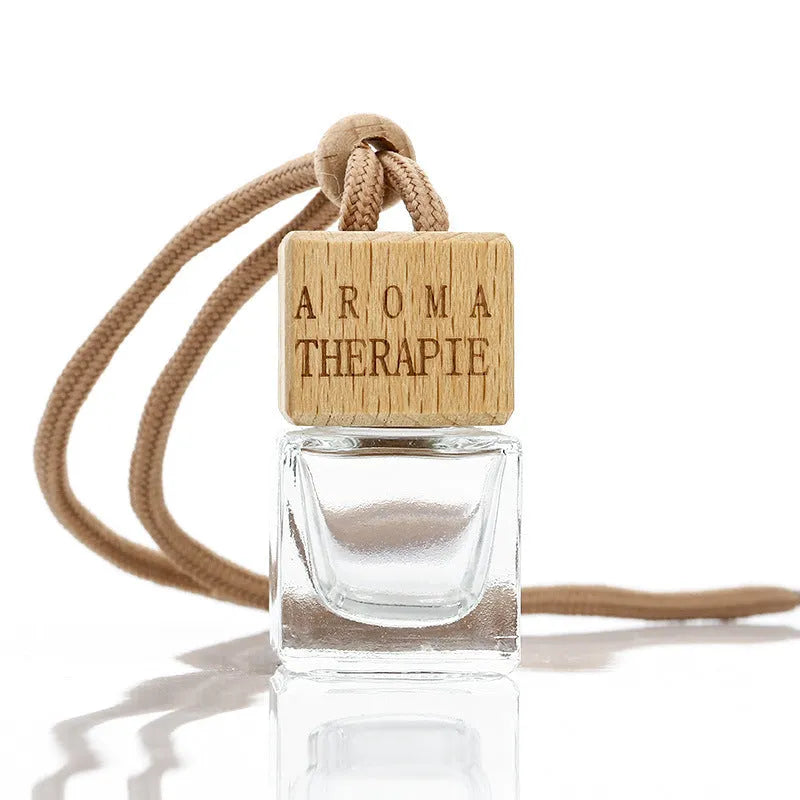 Square clear glass car fragrance pendant bottle with 8ml capacity hanging from a rearview mirror