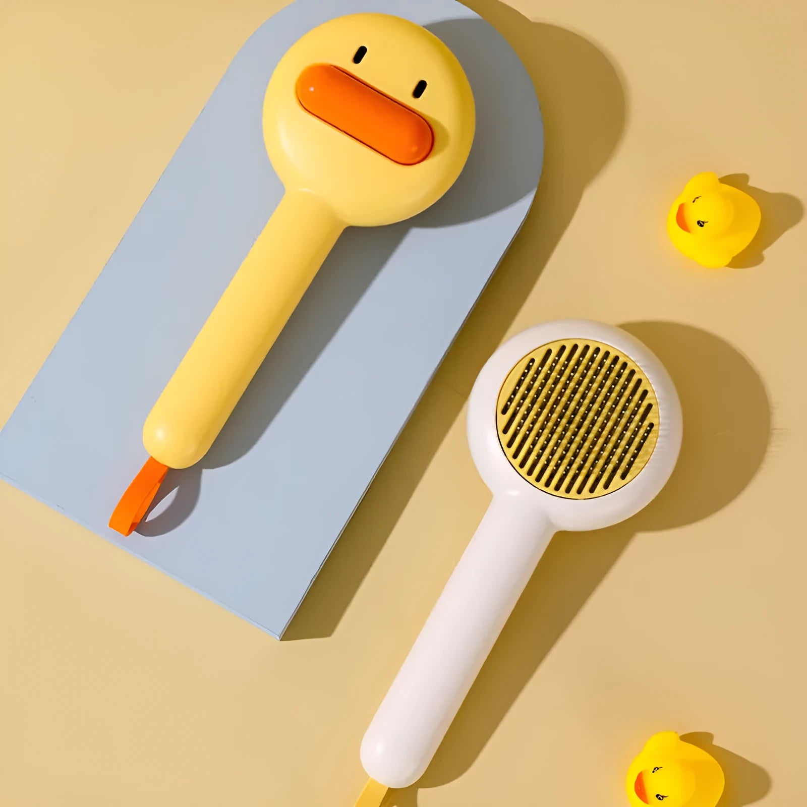 Small yellow duck-shaped pet grooming comb with needle tines for hair removal from cats and dogs.