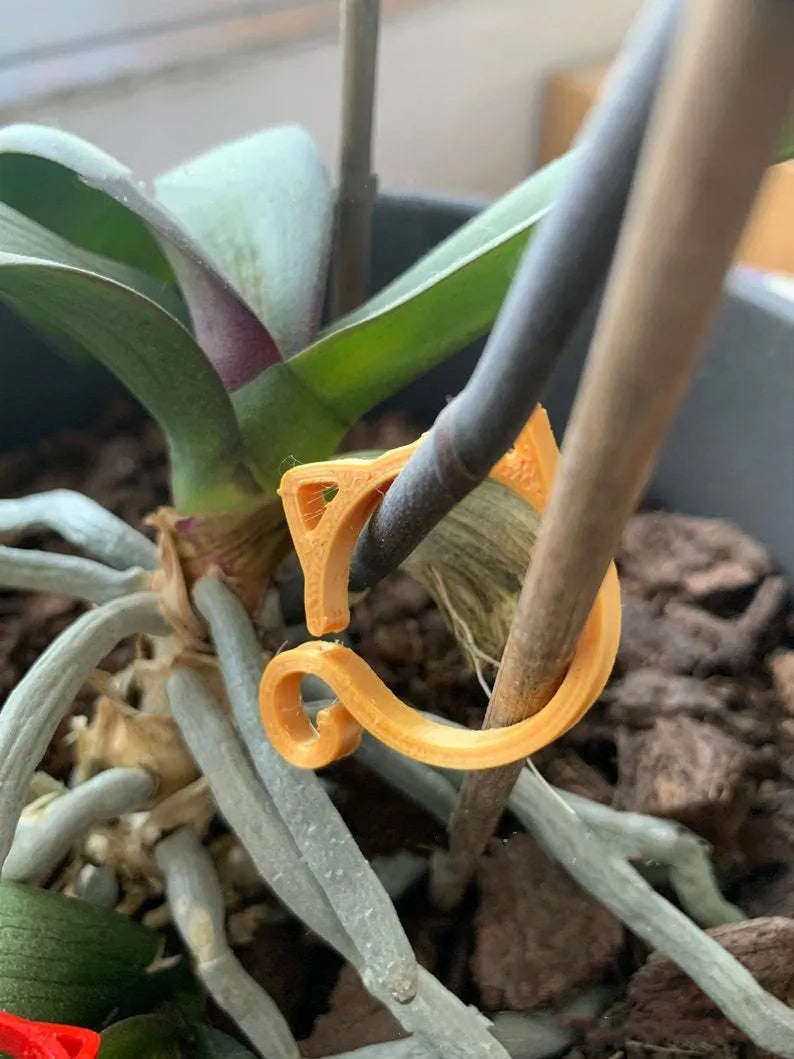 Colourful plastic cat-shaped clip for plant pots in red, yellow, green, and white.