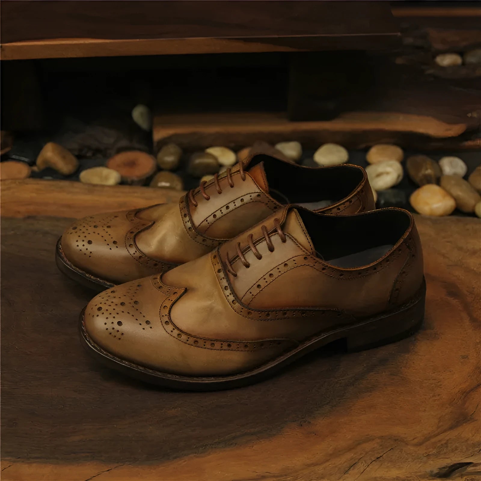 Men's light brown leather lace-up shoes with hand-carved distressed detailing on a wooden background.