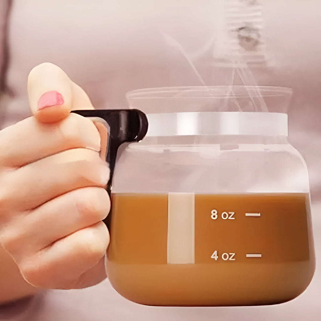 Transparent borosilicate glass coffee maker with black silicone lid on a stovetop