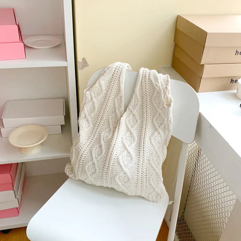 Light brown crochet knit tote bag with double shoulder straps on a wooden table.