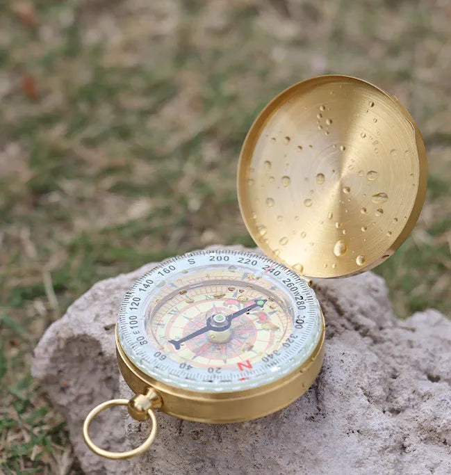 Gold brass flip compass with luminous dial and lid closed, 50mm diameter for outdoor navigation