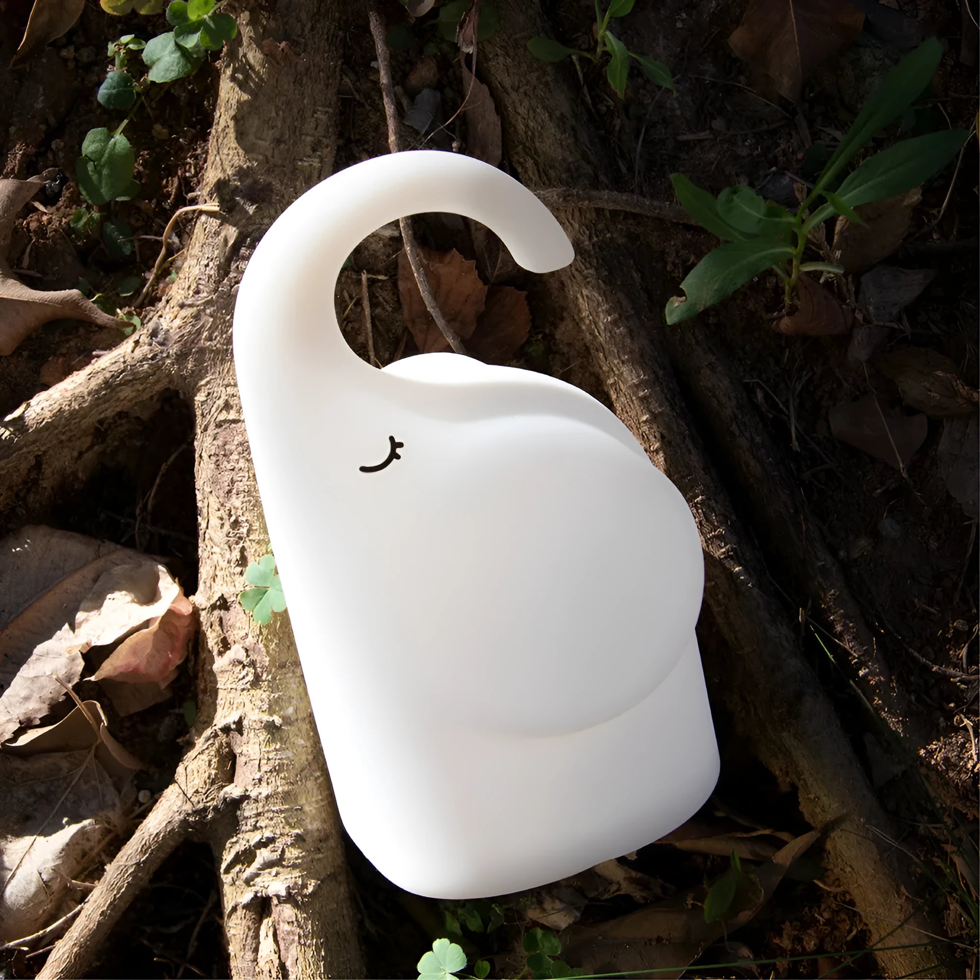 White silicone elephant-shaped night light with a warm glow on a bedside table.