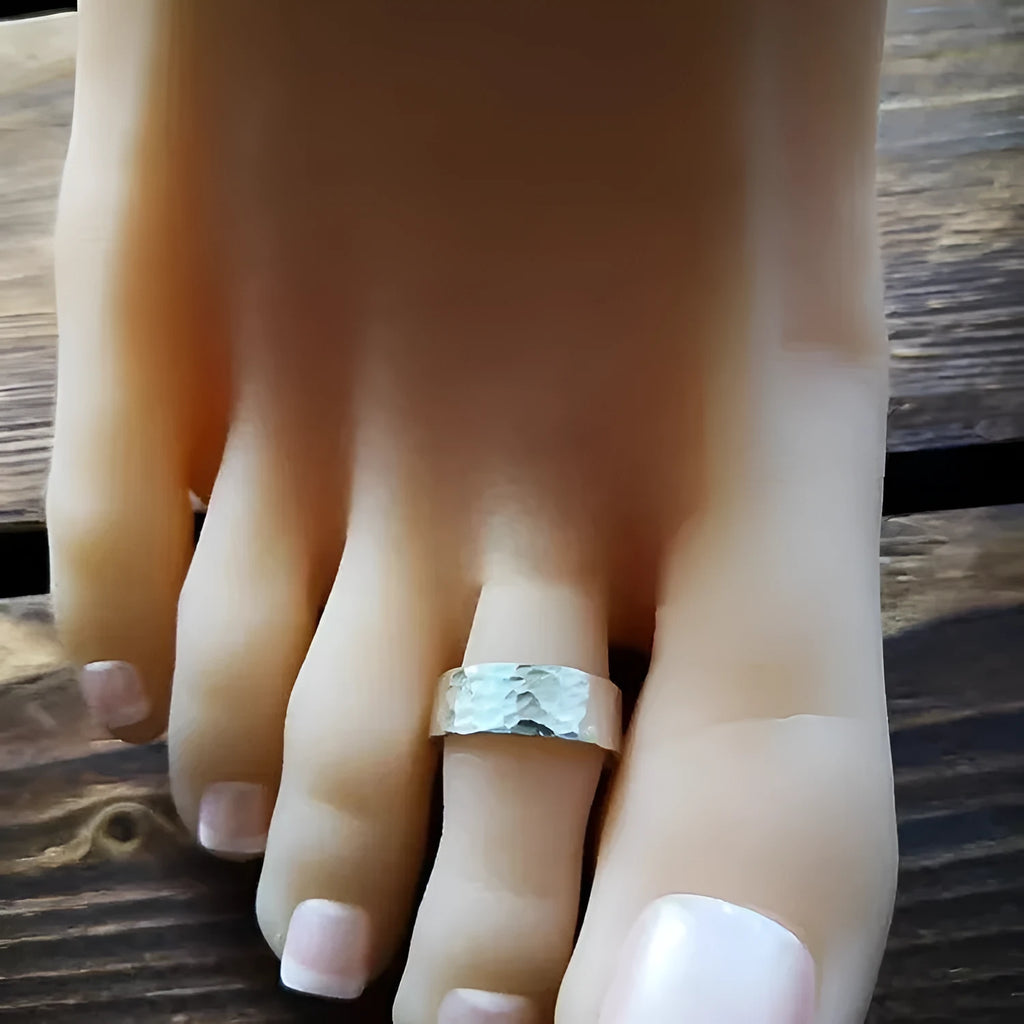 Golden hand-hammered alloy toe ring with open design on a woman's foot