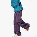 Men's waterproof loose casual pants in Graphite Black for outdoor use, side view on mountain trail