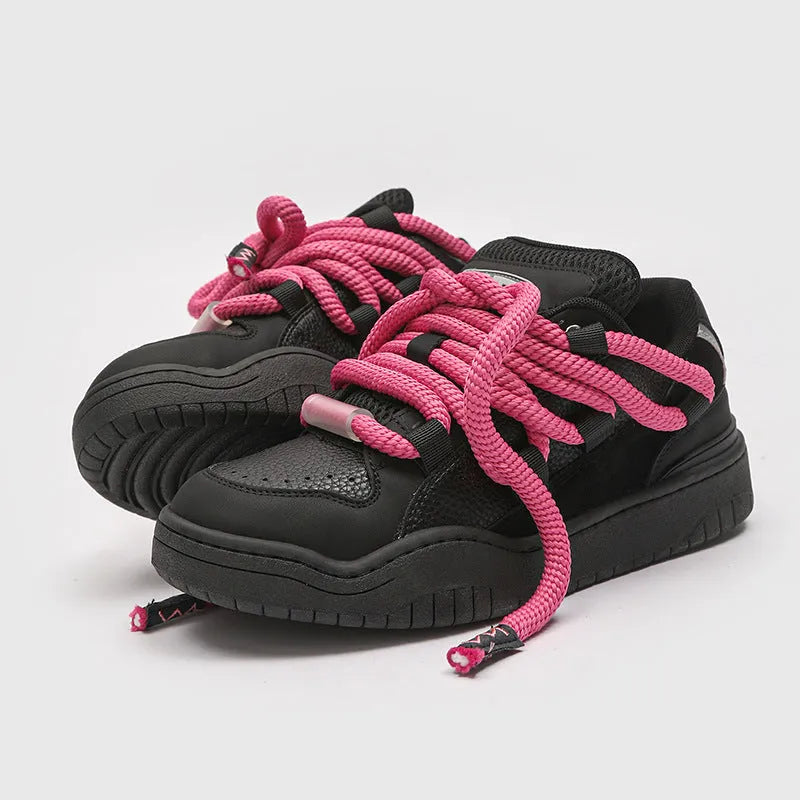 Pair of low-top unisex casual sneakers with thick flat rubber sole and lace-up front in a solid colour.