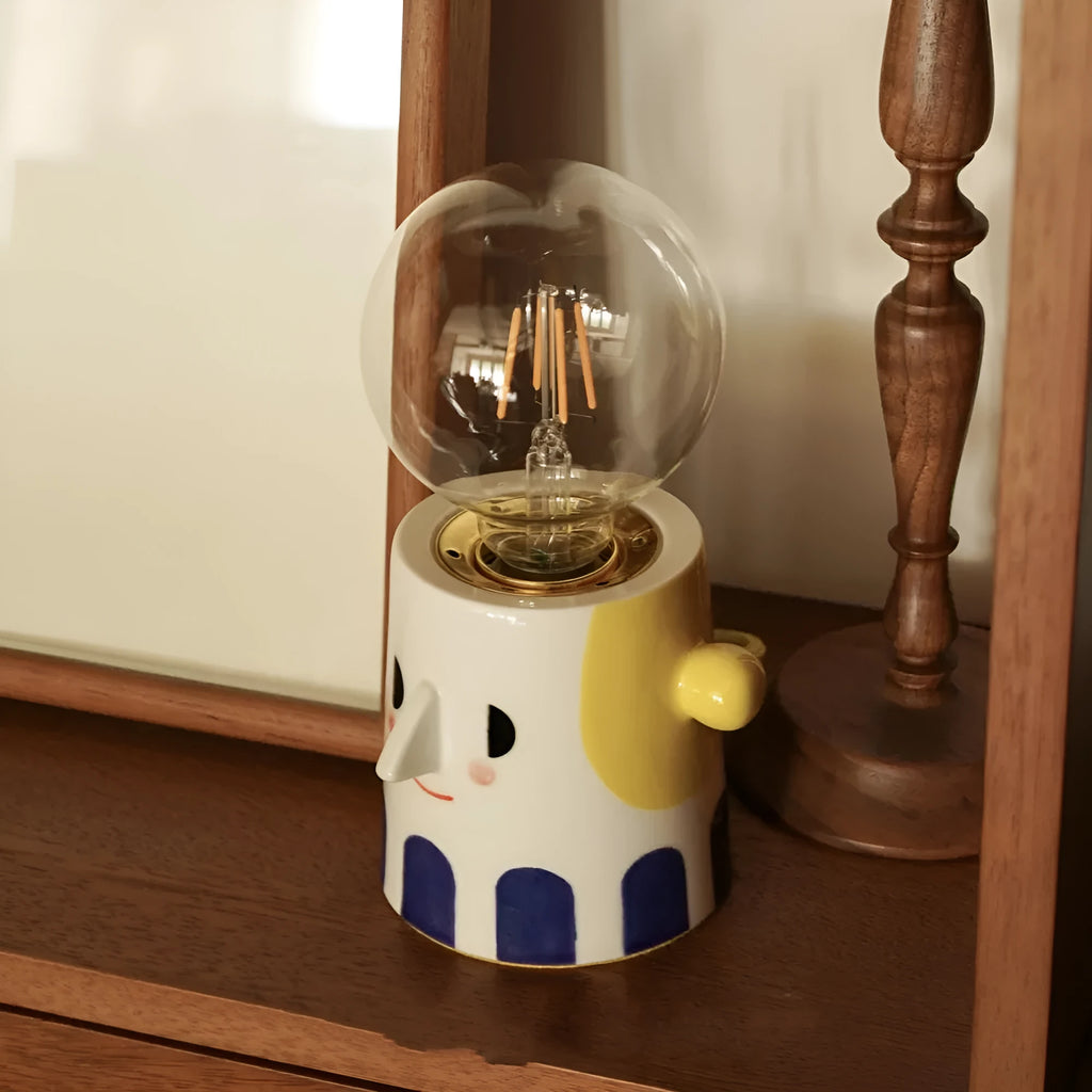 Handmade solid ceramic table lamp with spherical white shade on a wooden surface, showing UK plug.