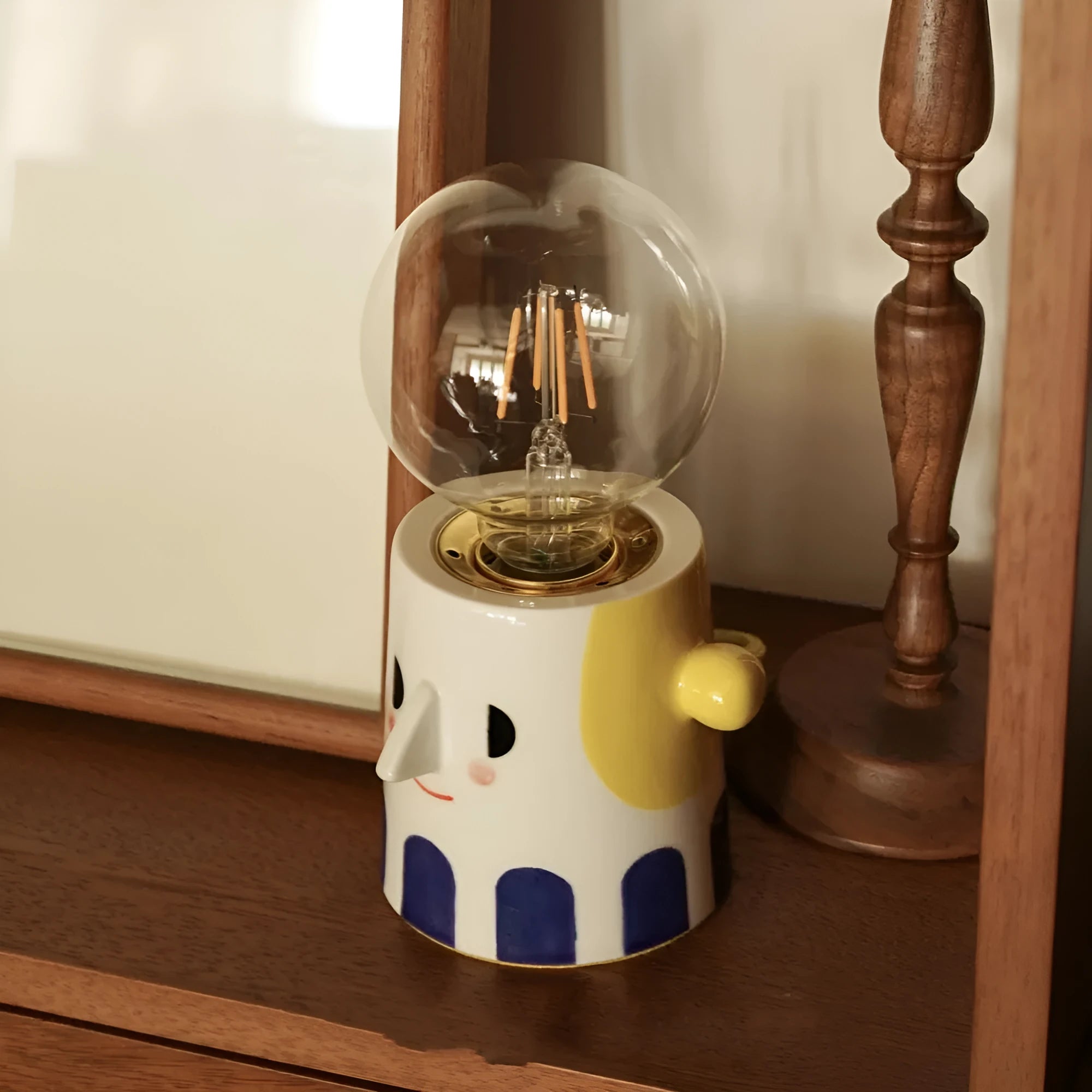 Handmade solid ceramic table lamp with spherical white shade on a wooden surface, showing UK plug.