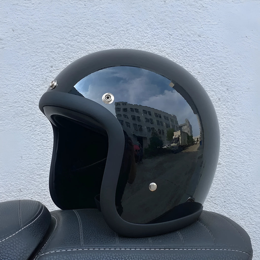 Retro-style half motorcycle helmet in fibreglass, shown in Cement Grey colour on a stand.