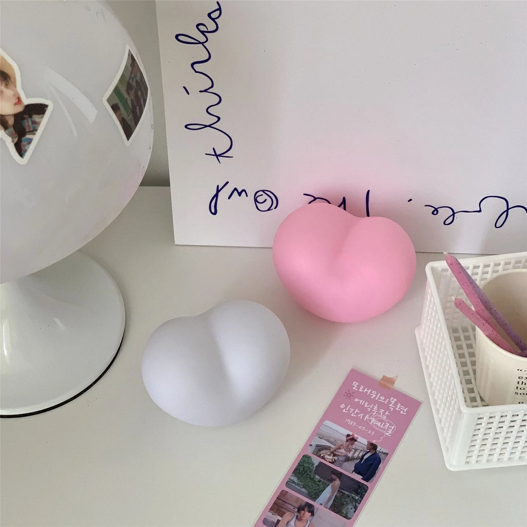 White and pink vinyl atmosphere lamp in trumpet and tuba shapes on a bedside table.