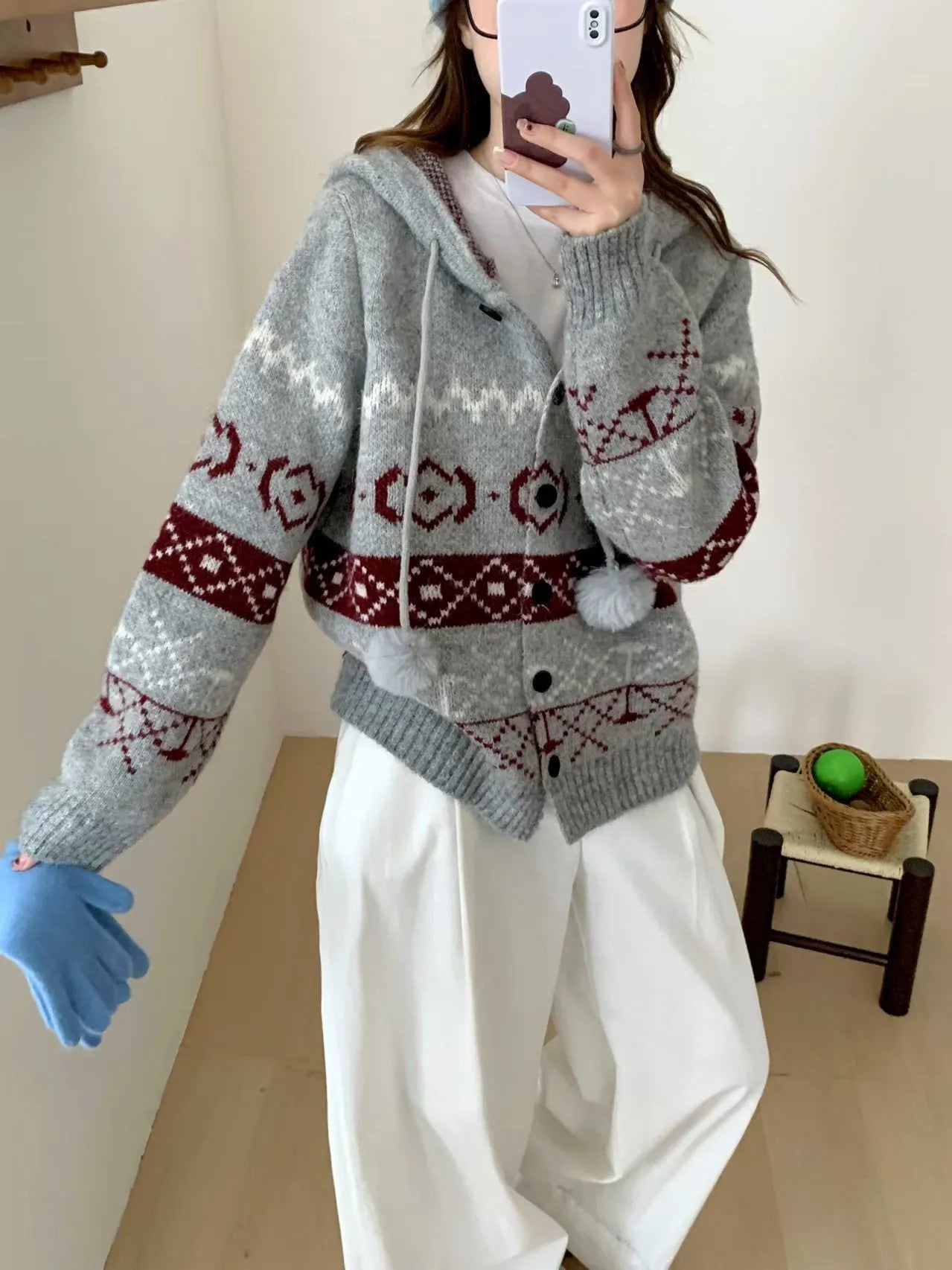 Woman wearing a beige loose-fit brocade sweater coat with a geometric pattern and long sleeves.
