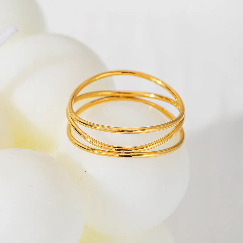 Gold geometric coil ring on a plain background, showing its three-layer titanium steel construction