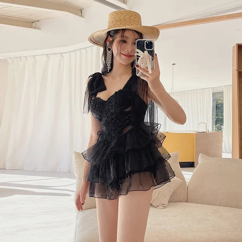 Black sleeveless one-piece swimsuit with gathered chest detail on a mannequin.