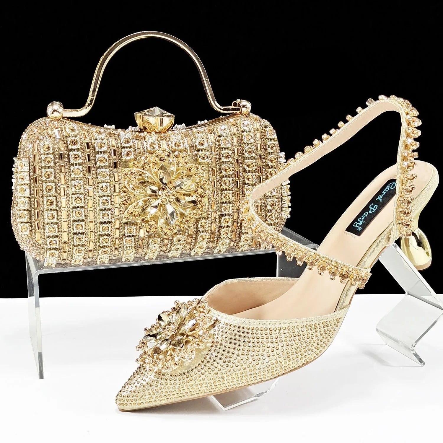 Women's black high-heel ankle boots with chain buckle flower decoration and a matching hard clutch bag.