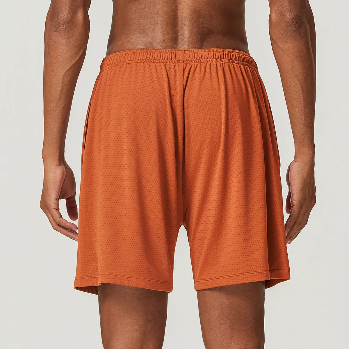 Man wearing brick red double-layer running shorts with a moisture-wicking fabric and inner compression liner.