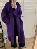 Woman wearing a longline loose grey hooded cardigan coat with raglan sleeves.