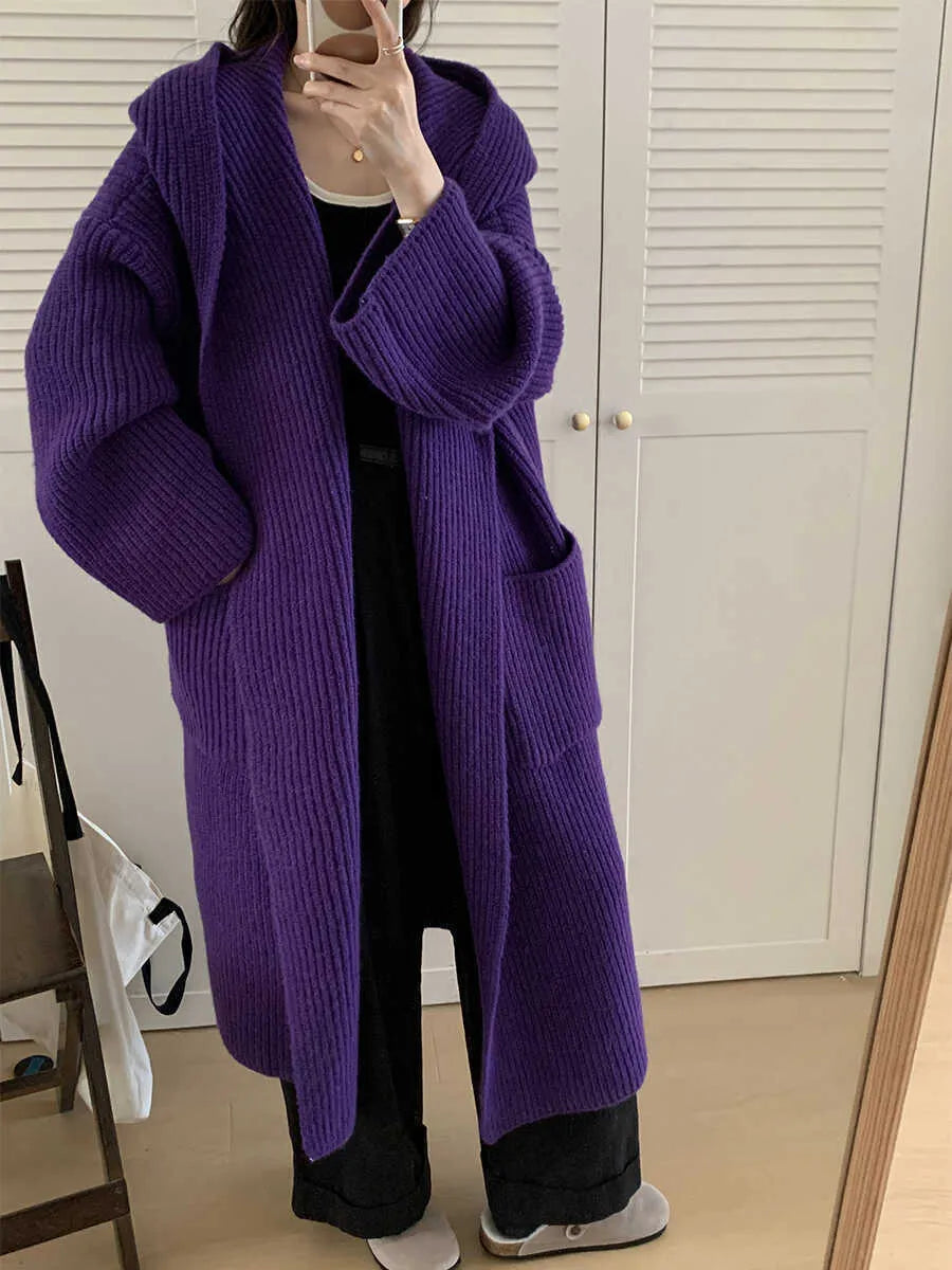 Woman wearing a longline loose grey hooded cardigan coat with raglan sleeves.