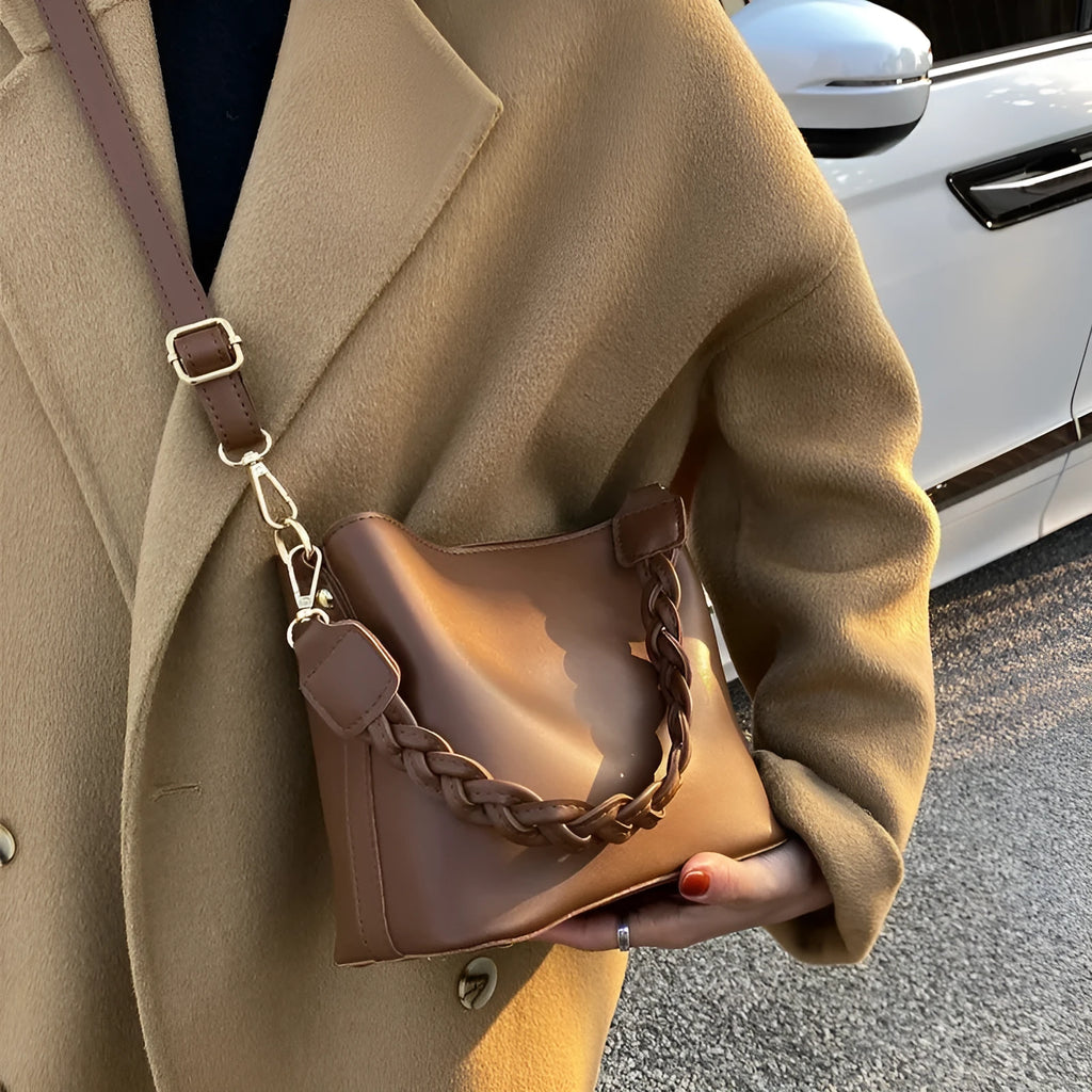 Retro style khaki woven PU leather crossbody bucket bag with an adjustable strap, shown in a casual setting.