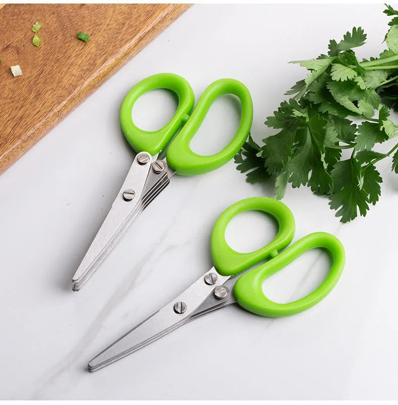 Stainless steel multi-layer kitchen scissors for cutting green onions and herbs on a chopping board.