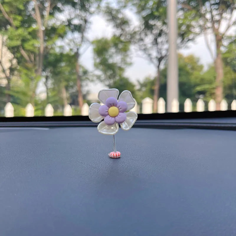 Small colourful plastic car decoration shaped like a swing, shown in blue, on a car dashboard.