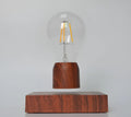 Magnetic levitation desk lamp with a floating glass bulb above an imitation wood base.